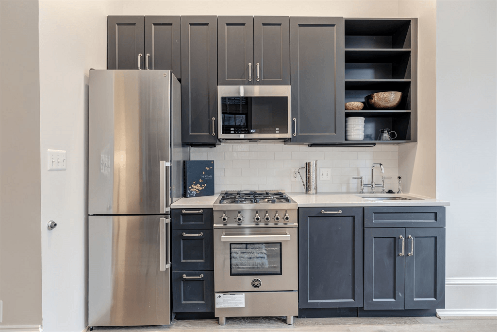 a kitchen with gray cabinets and a stainless steel refrigerator